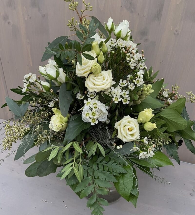 Blumenstrauß mit weißen Rosen und grünen Blättern vor hellem Hintergrund. Elegante Blumendekoration für besondere Anlässe.